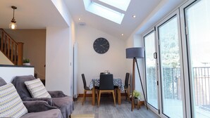 Ein modernes Wohnzimmer mit einer Couch, einem Esstisch und einem großen Fenster.