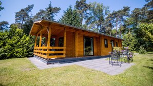 Une cabane en bois avec un porche, une terrasse avec des chaises et un jardin.