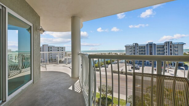 Un balcon donnant sur un parking, des immeubles et une plage.