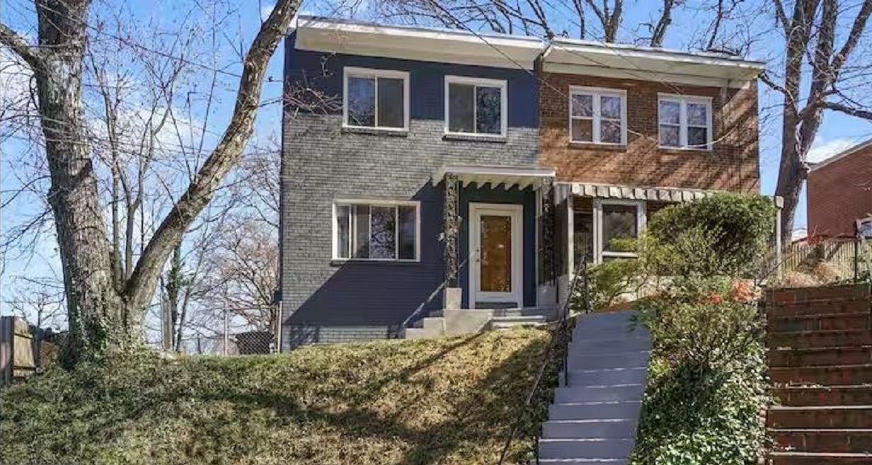 A two-story house with a front porch, a visible staircase, and a brick facade.
