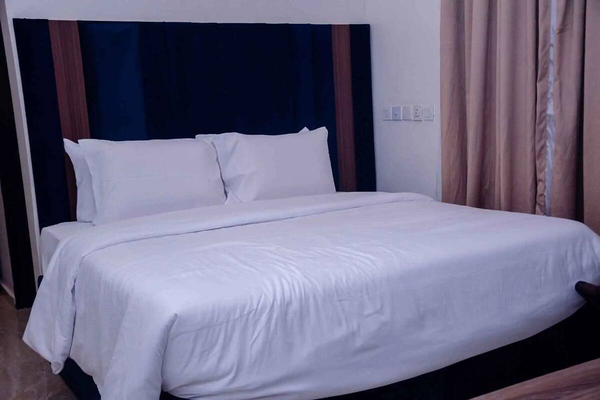 Un lit bien fait, avec du linge de lit blanc, dans une chambre d’hôtel.