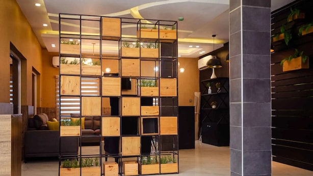 A modern interior with a wooden partition, a sofa, and a black cabinet. - Ibizza Pit Hotel and Suites (Lagos)