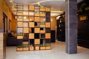 A modern interior with a wooden partition, a sofa, and a black cabinet. - Ibizza Pit Hotel and Suites (Lagos)