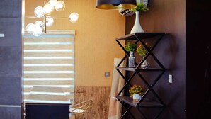 A modern interior with a wooden wall, a black metal shelf with plants, and a ceiling light fixture. - Ibizza Pit Hotel and Suites (Lagos)
