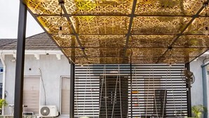 An outdoor seating area with checkered flooring, yellow and green chairs, and a patterned ceiling. - Ibizza Pit Hotel and Suites (Lagos)