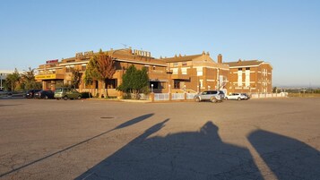 Un hotel con varios pisos, un estacionamiento y varios coches aparcados.
