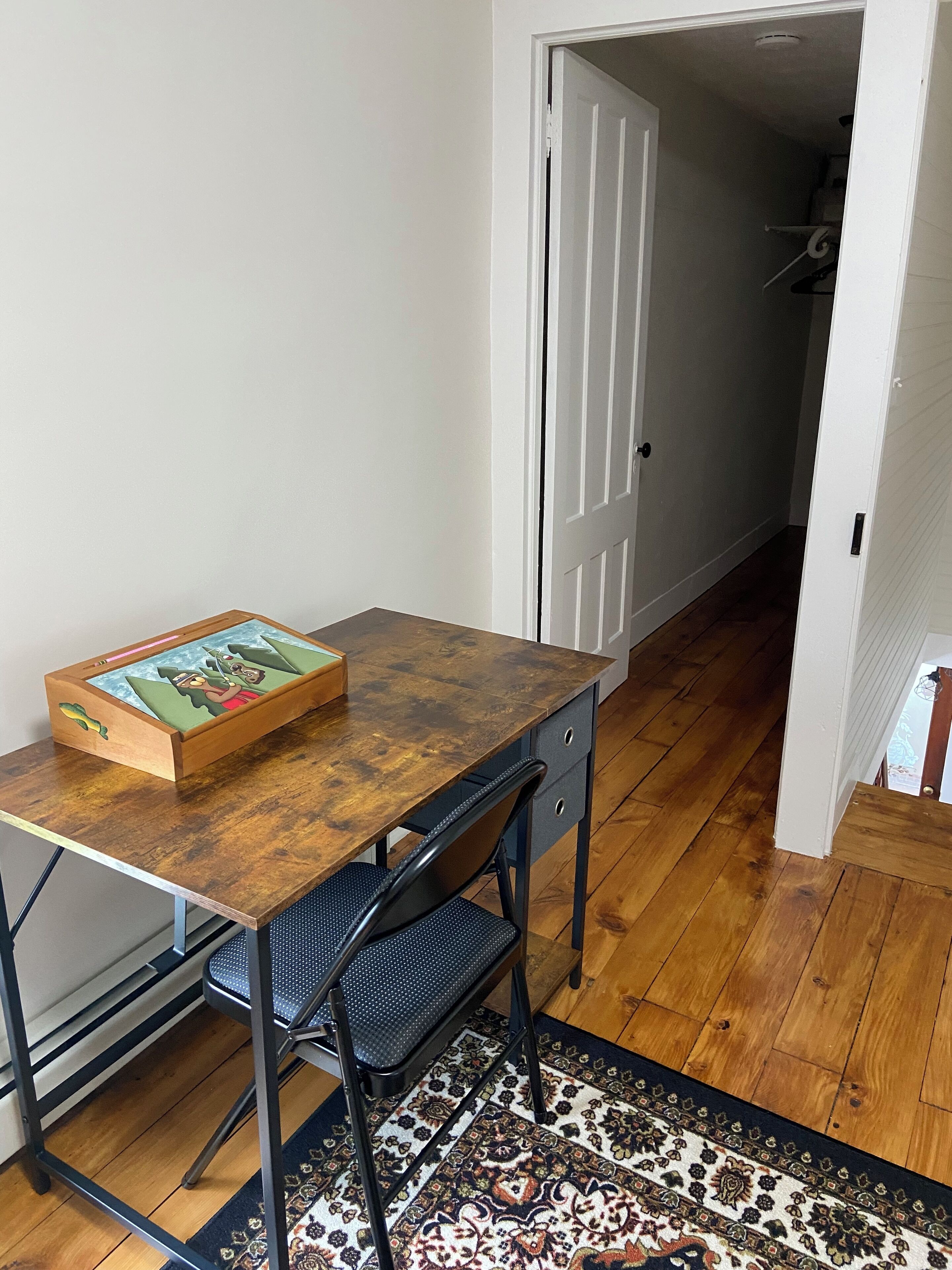 A small dining area with a wooden table, a chair, and a rug.