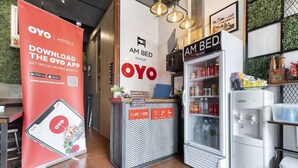 Un espace d’accueil d’hôtel avec une grande publicité pour la chaîne OYO Hotels, un comptoir de réception et un mini-réfrigérateur.