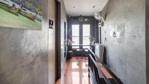 Un couloir avec un plancher en bois, un bureau et une chaise. Il y a une porte avec une pancarte au-dessus.