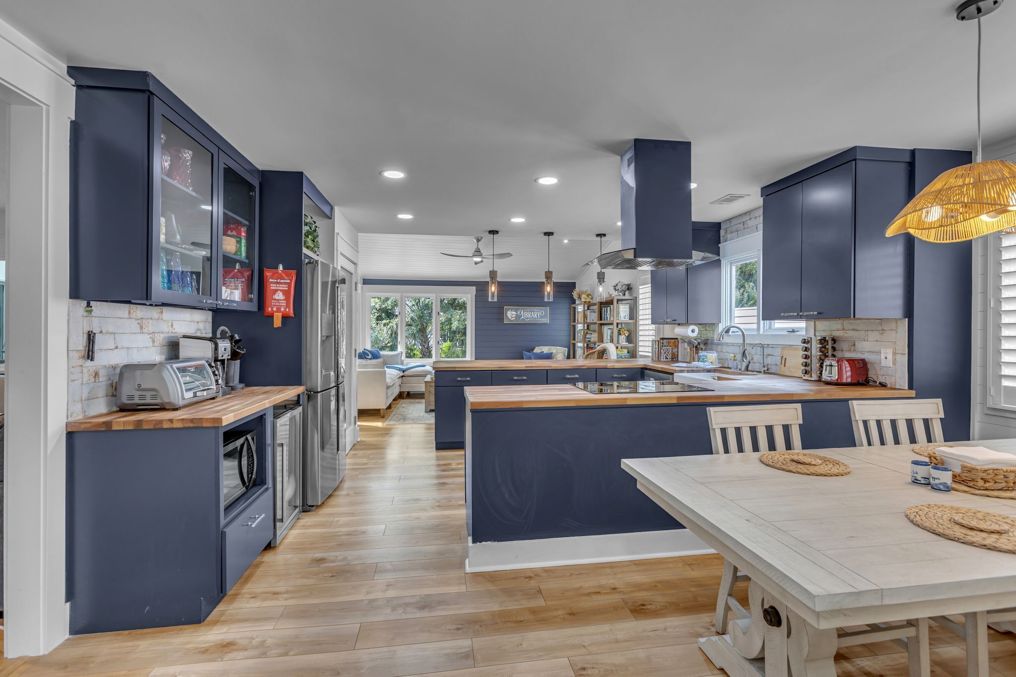 Een moderne keuken met donkere kastjes, een centraal eiland en een eetgedeelte met een witte tafel.