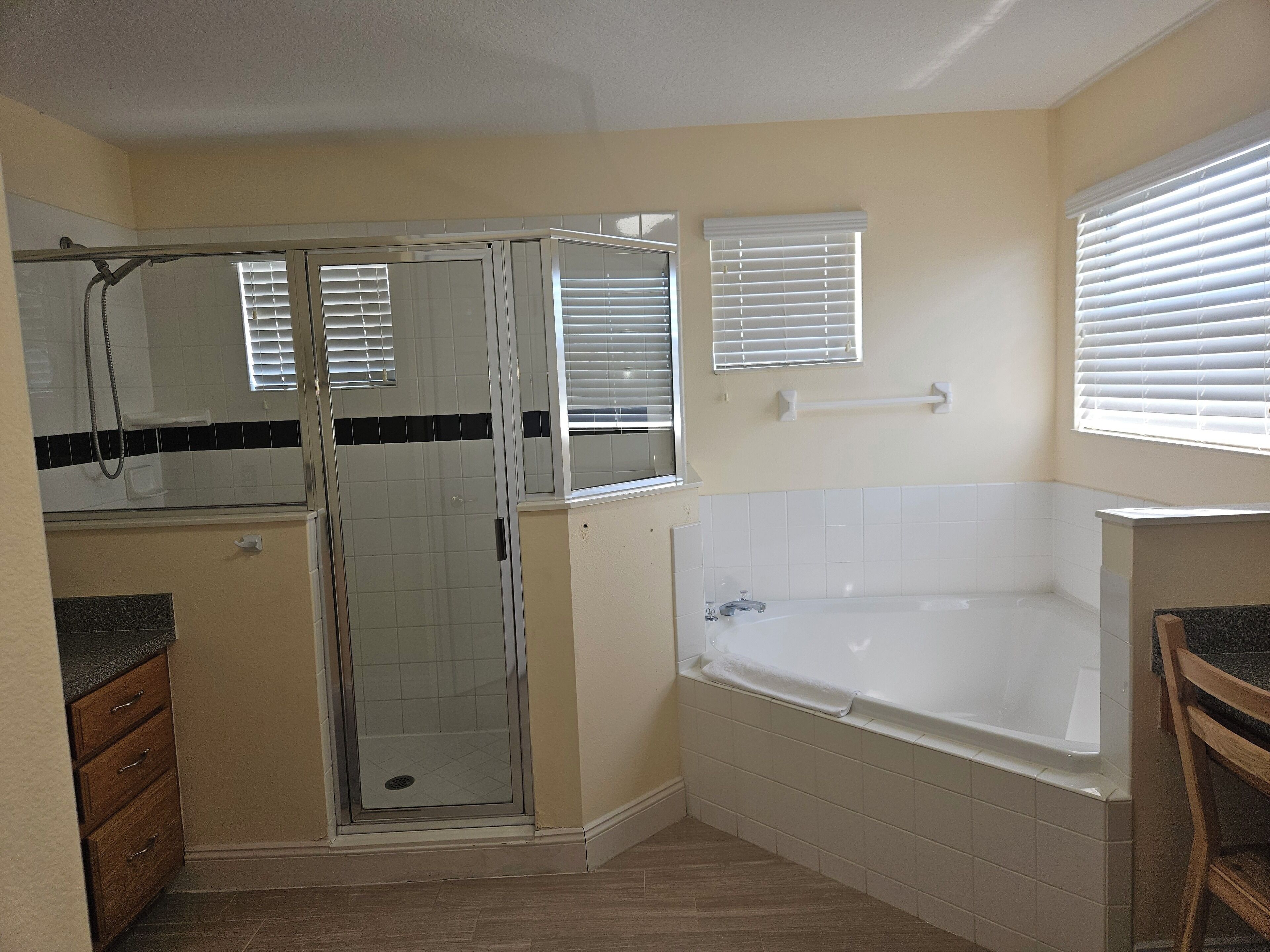 A bathroom with a shower, a bathtub, and a vanity with drawers.