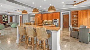 A spacious kitchen with a central island, wooden cabinets, and a dining area with bar stools.