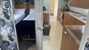 Una habitación pequeña con una cama litera, un kitchenette y un baño.