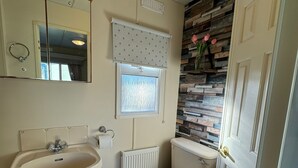 Un baño con lavamanos, inodoro y espejo.