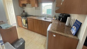 Una cocina compacta con armarios de madera, estufa, pileta y ventana.