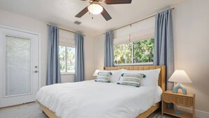 A bedroom with a bed, a ceiling fan, a nightstand with a lamp, and a window with curtains. - 3 Blocks to Beach ☀️ Game room, cabana bar + family fun (Holmes Beach)