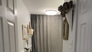Un pasillo estrecho que conduce a un baño con inodoro, lavabo y un armario negro.