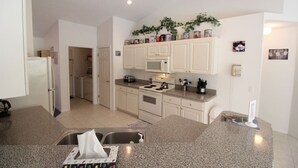 A modern kitchen with white cabinets, granite countertops, a microwave, stove, and a sink. - Inverness Florida 4BR Pool Home & Spa – Near Ocala, Crystal River & Floral City (Inverness)