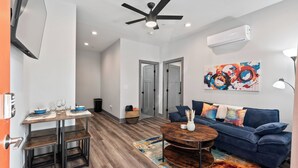 A modern living room with a blue sofa, a wooden coffee table, and a dining area with a table set for four.