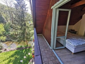 A bedroom with a large window, a bed, and a view of a pond and trees. - Fairy Tale Cottage on Water Stream, 30 Minutes From South Prague (Petrov)