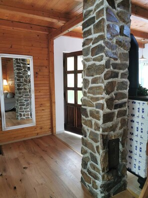 A stone pillar in a wooden room with a door and a mirror reflecting part of the room. - Fairy Tale Cottage on Water Stream, 30 Minutes From South Prague (Petrov)