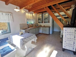 Una cocina acogedora con vigas de madera, una zona de comedor con cojines azules y suelo de baldosas.