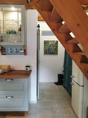 Una cocina con techo de madera, un aparador de vidrio con vajilla y un cuadro en la pared.