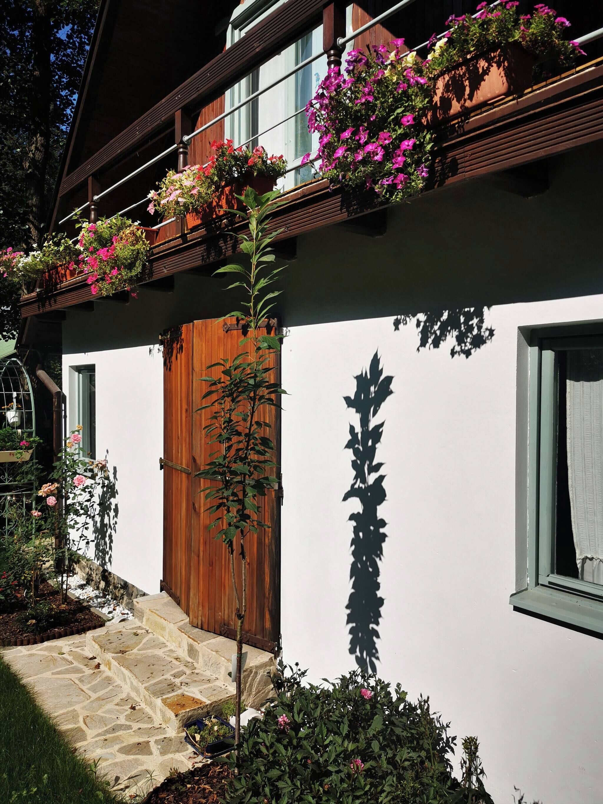 Un edificio tradicional con puerta de madera, escalones de piedra y jardineras en el nivel superior.
