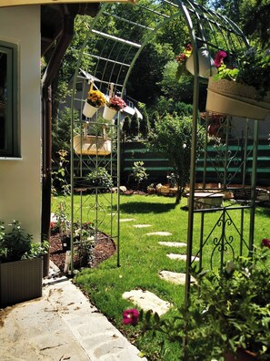 A garden with a metal pergola structure, potted plants, and a stone pathway. - Fairy Tale Cottage on Water Stream, 30 Minutes From South Prague (Petrov)