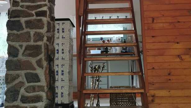 Interior de madera con un pilar de piedra, una escalera de madera y una ventana.