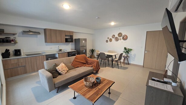 A modern apartment with a living room, kitchen, dining area, and a small balcony. - Modern Beach Condo, Jaco (Jacó)