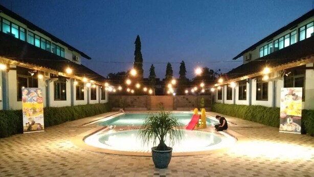 A swimming pool with a slide, surrounded by a tiled patio area. - Hotel Sofia Juanda Surabaya (Sidoarjo)