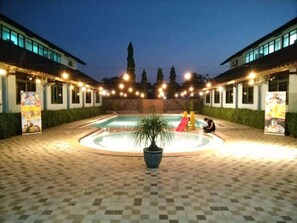 Une piscine avec un toboggan, entourée d’une terrasse carrelée.