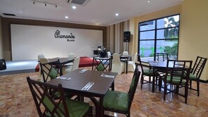 A conference room with tables and chairs, a stage with a drum set, and a large window with a view. - Hotel Sofia Juanda Surabaya (Sidoarjo)