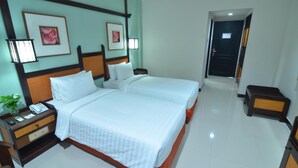 A hotel room with two beds, a nightstand with a lamp, and framed pictures on the wall. - Hotel Sofia Juanda Surabaya (Sidoarjo)
