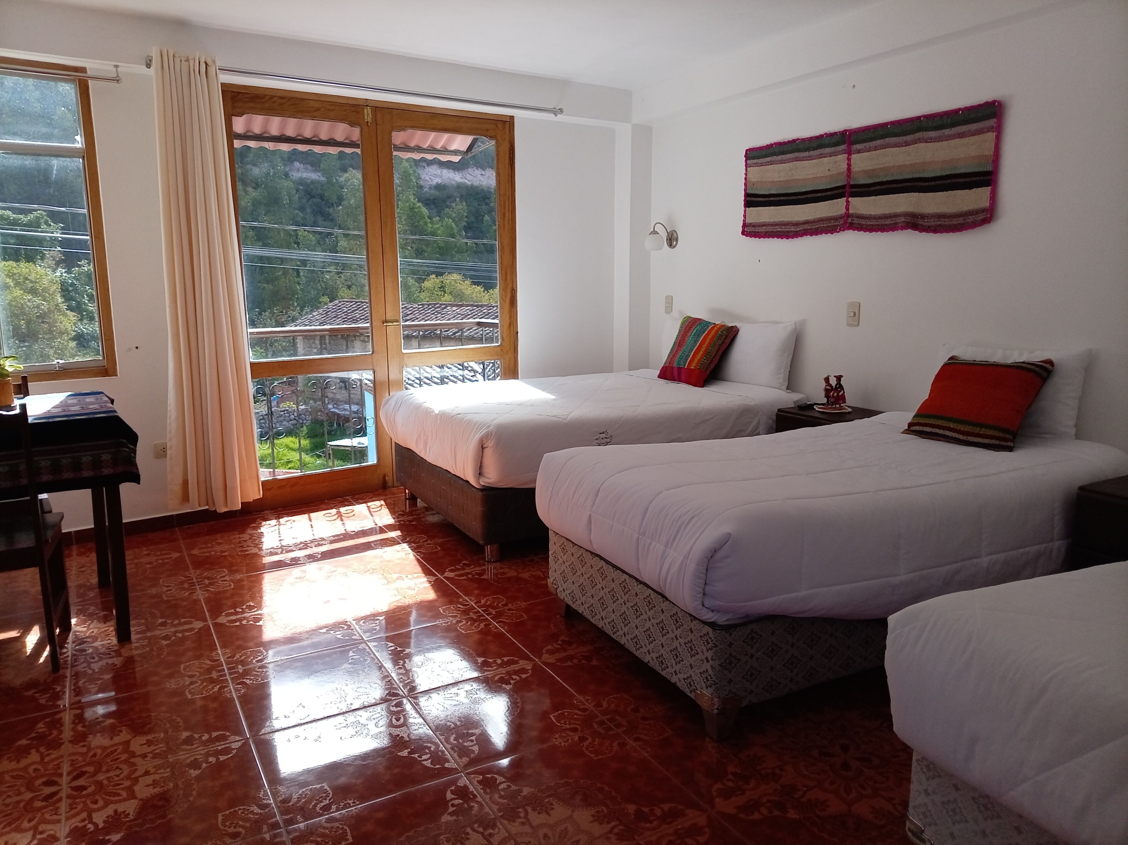 A room with two beds, a table, and a window with curtains.