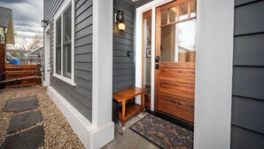 A house with a gray siding exterior, a wooden front door, and a bench outside.