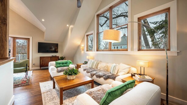 A spacious living room with a high ceiling, large windows, and a modern fireplace.