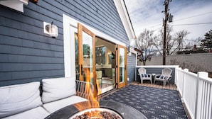 A patio with a fire pit, outdoor seating, and a covered area with a sliding glass door.