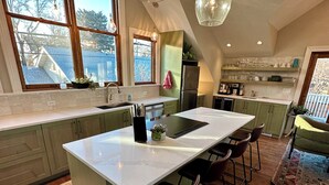 A modern kitchen with a central island, bar stools, and pendant lighting.