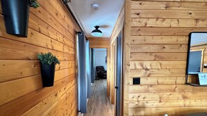 A wooden interior hallway with a ceiling light, a potted plant, and a door leading to another room. - Cozy 1-bedroom apartment unit C, sleeps 6  across from famous Cody Nite Rodeo! (Cody)