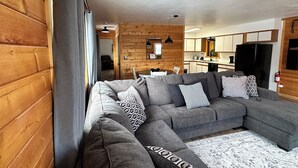 A modern living room with a grey sectional sofa, patterned cushions, and a patterned rug. - Cozy 1-bedroom apartment unit C, sleeps 6  across from famous Cody Nite Rodeo! (Cody)