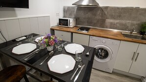 A compact kitchen with a microwave, washing machine, and a wooden countertop. - Apartment Duplo 08 (Madrid)