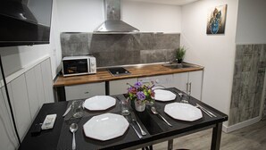 A modern kitchen with a microwave, stove, and sink. There is a dining table set with plates, cutlery, and a vase with flowers. - Apartment Duplo 08 (Madrid)