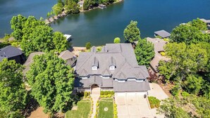 A large house with a spacious front yard, a driveway, and a lake view.