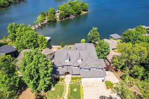 A large house with a spacious front yard, a driveway, and a lake view.