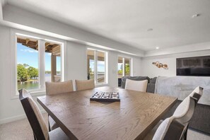A spacious room with a large dining table, multiple chairs, a sofa, and a TV.