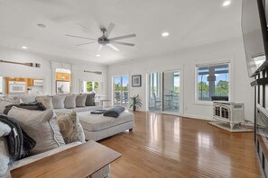 A spacious living room with a large sofa, a coffee table, and a ceiling fan.