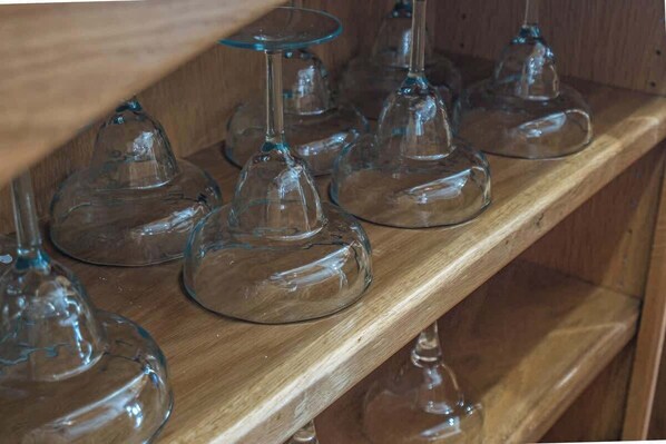 Una estantería de madera con varias copas de cristal transparente para vino.