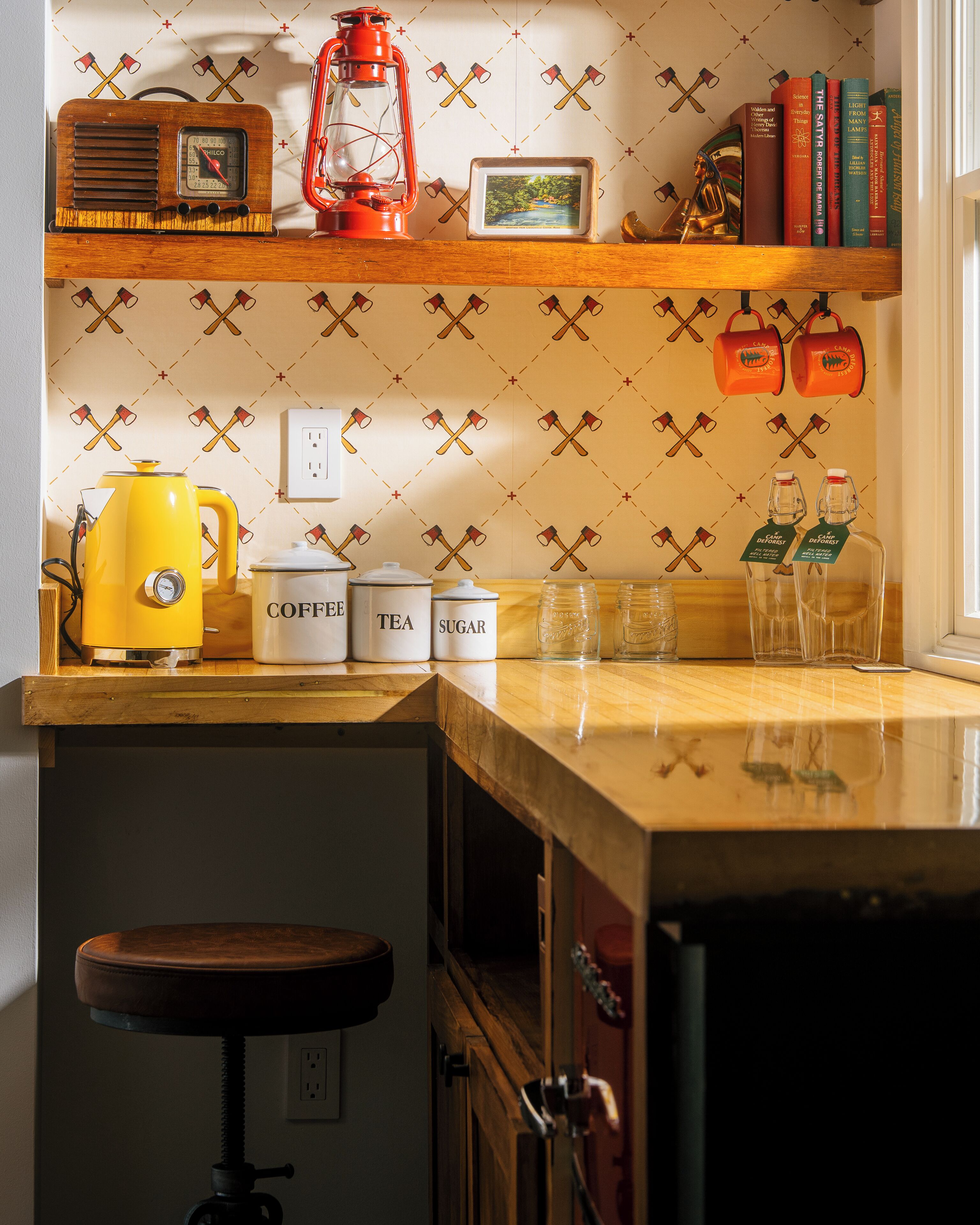 A kitchen with a wooden countertop, a yellow kettle, a coffee maker, tea and sugar containers, and a red lantern.